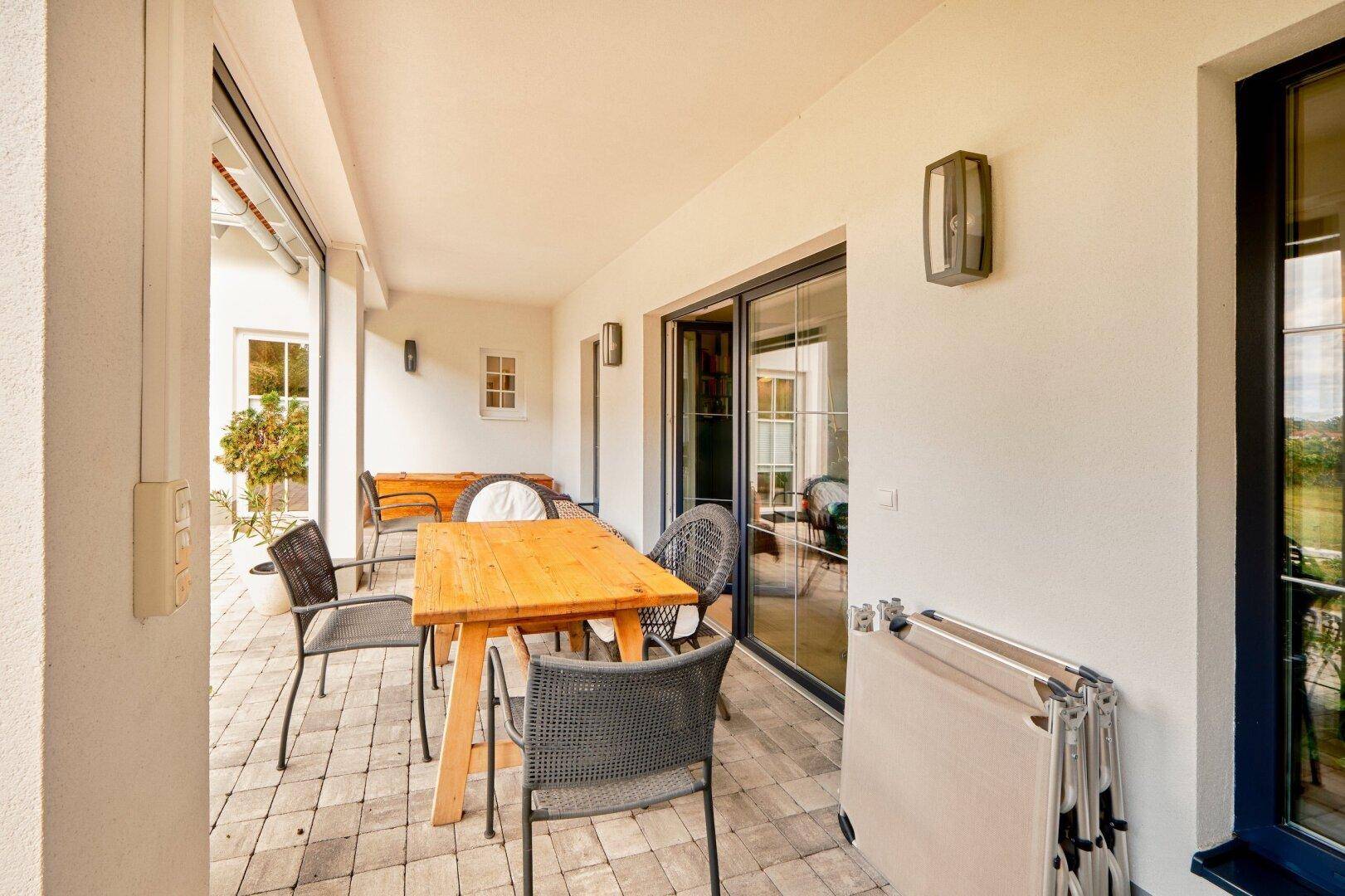 Überdachte Terrasse mit Holztisch und Stühlen, ideal für entspannte Stunden im Freien.