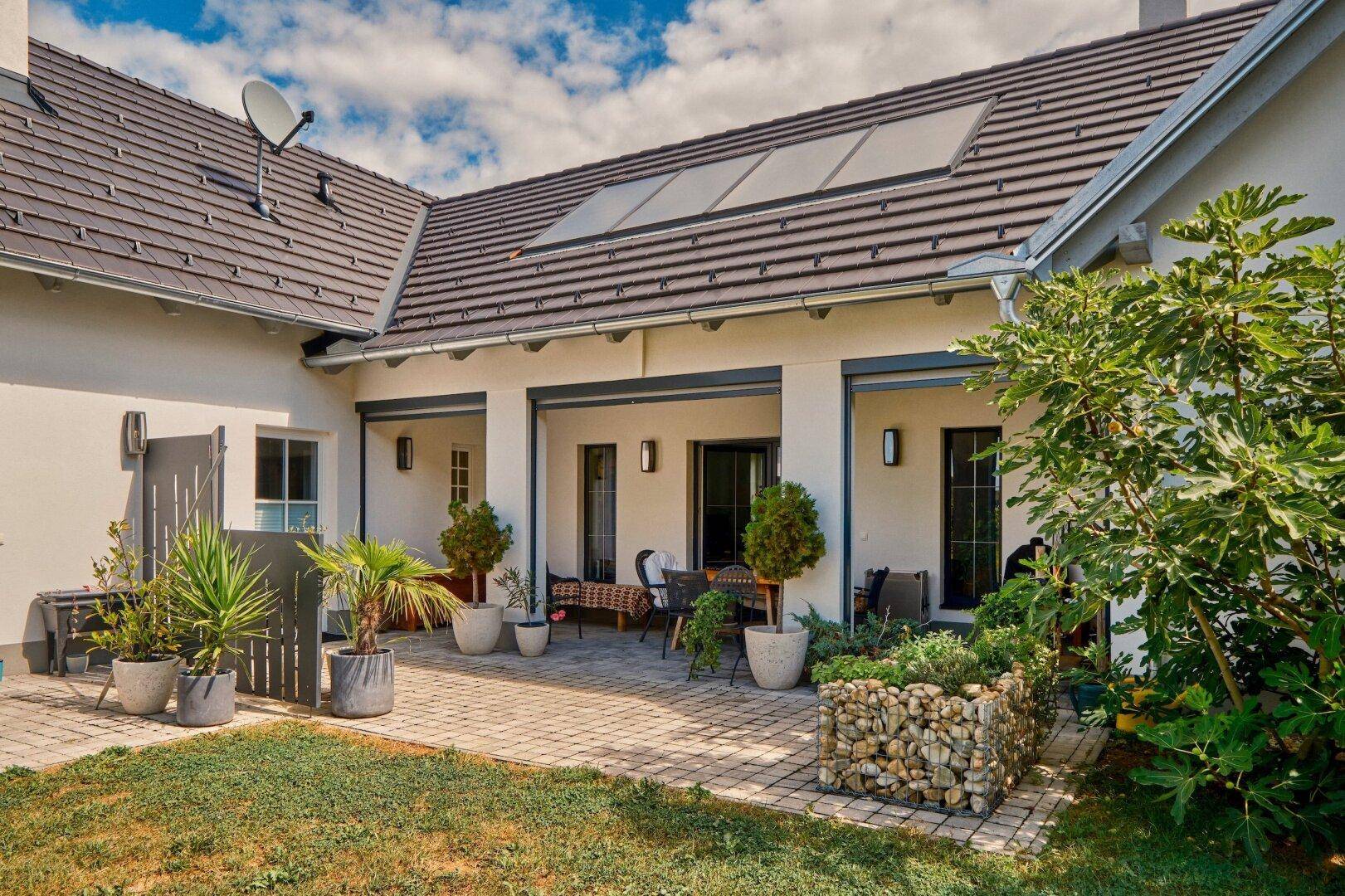 Gemütliche gepflasterte Terrasse mit Sitzgelegenheiten und Pflanzen, direkt am Haus gelegen.