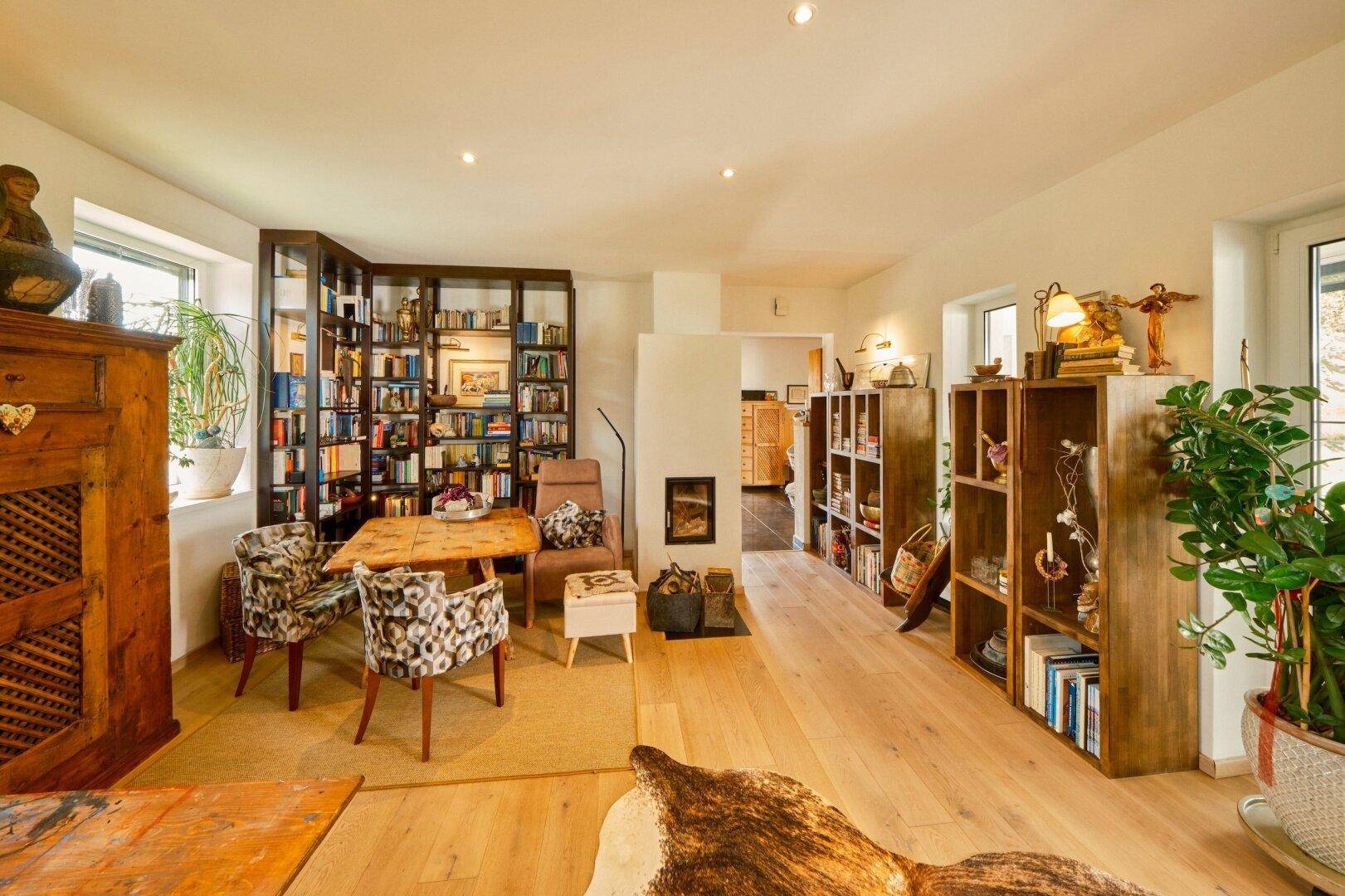Heller Wohn-Essbereich mit Kamin, Holzboden und umfangreicher Bibliothek.