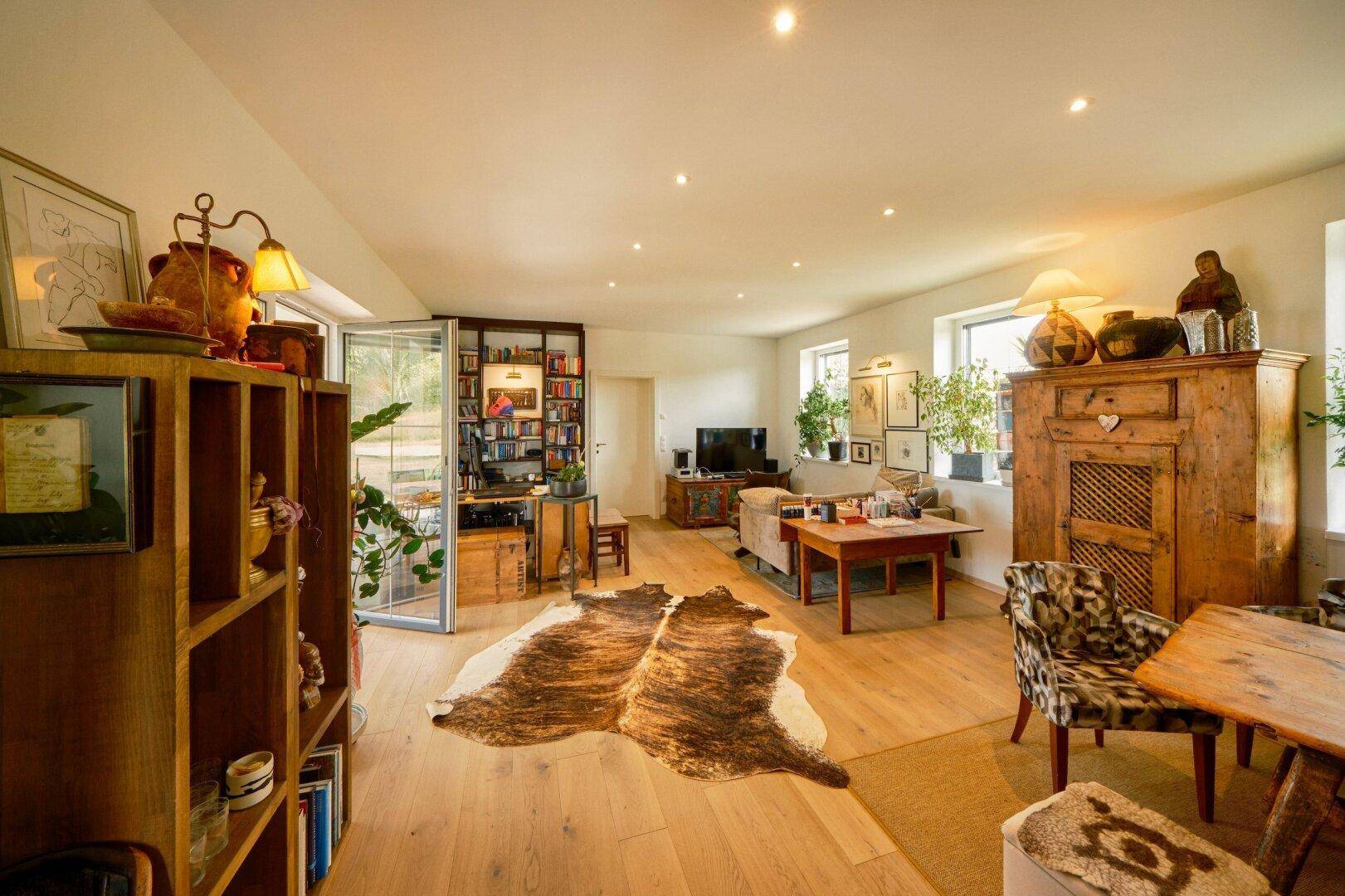 Helles Wohnzimmer mit Holzboden, gemütlichen Möbeln und einem Kuhfellteppich.