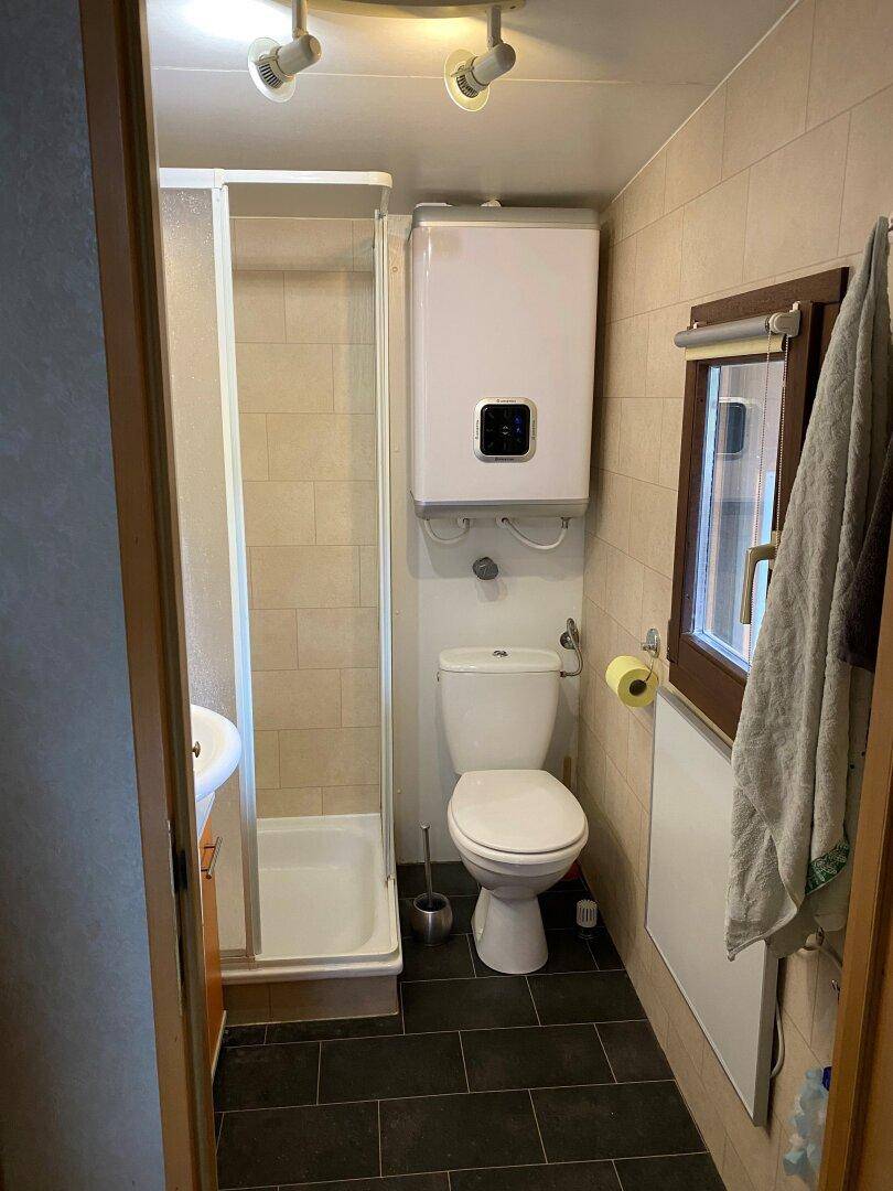 Funktionales Badezimmer mit Duschkabine, WC, Waschbecken und Fenster für Tageslicht.