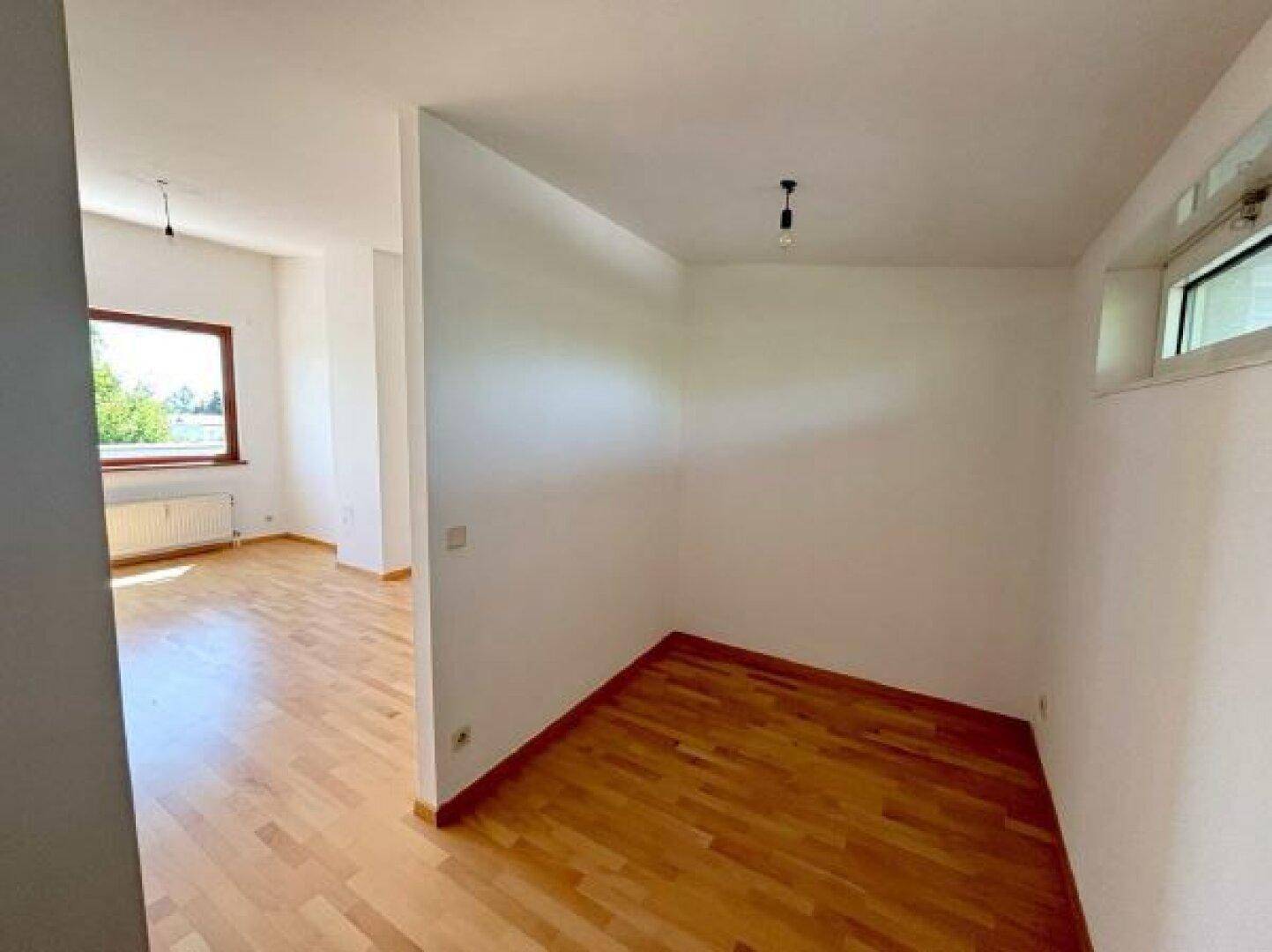 Heller Raum mit Parkettboden und einem Fenster, das viel Tageslicht hereinlässt, ideal für ein Schlafzimmer.