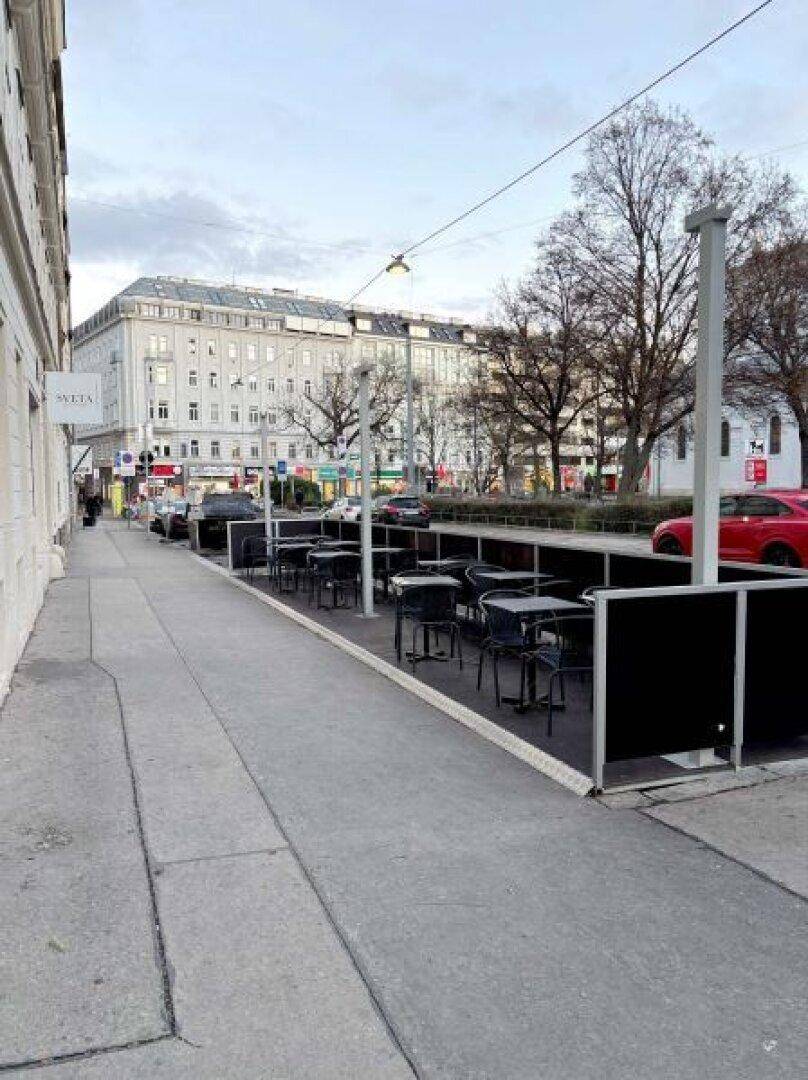 Außenbereich eines Cafés oder Restaurants mit Tischen und Stühlen auf dem Bürgersteig in der Stadt.