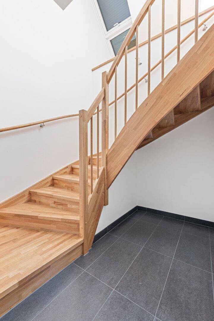 Holztreppe mit Metallgeländer, die zwei Etagen miteinander verbindet.