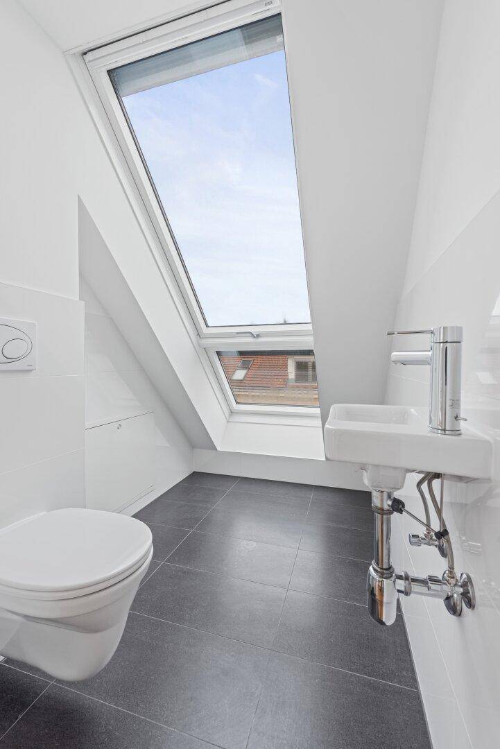 Modernes Badezimmer mit Toilette, Waschbecken und Dachfenster.