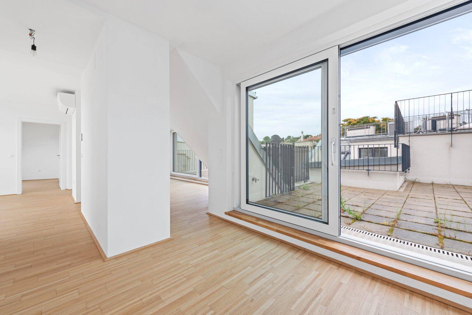 Wohnraum mit Zugang zu einer großen Dachterrasse durch eine breite Schiebetür.