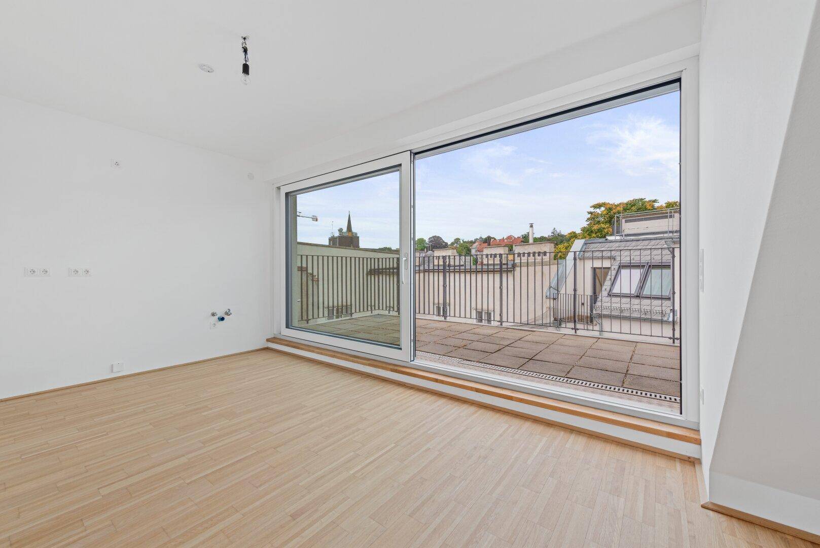 Heller Wohnbereich mit Schiebetür, die auf eine weitläufige Dachterrasse führt.