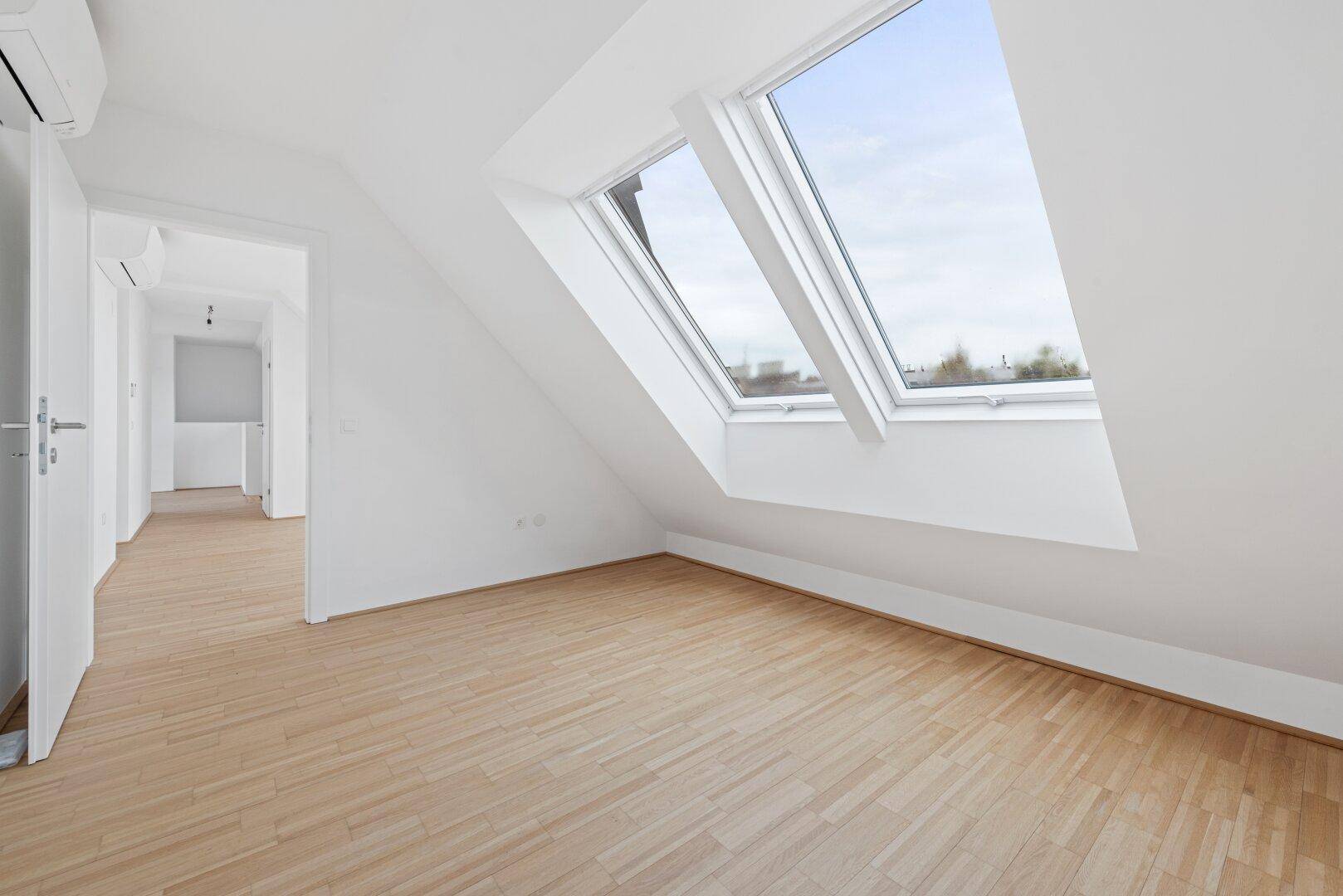 Helles Schlafzimmer im Dachgeschoss mit Dachfenstern und Klimaanlage.