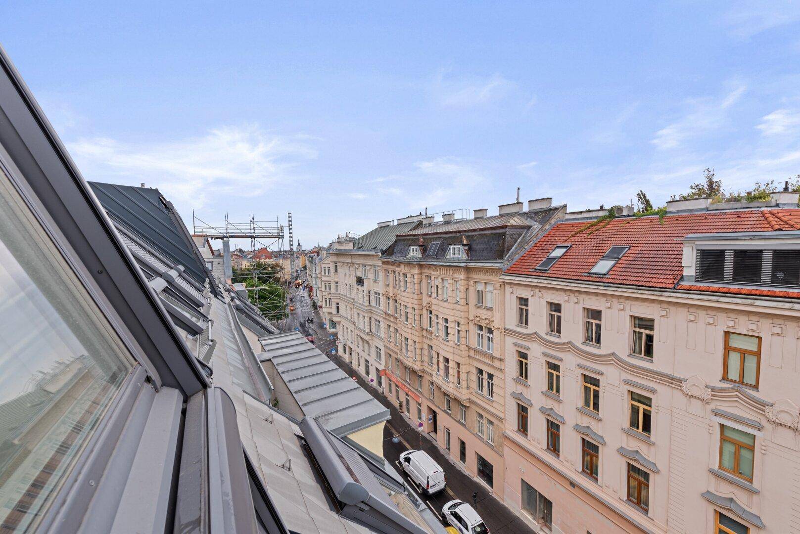 Blick von oben auf eine belebte Straße mit Gebäuden und Fahrzeugen.