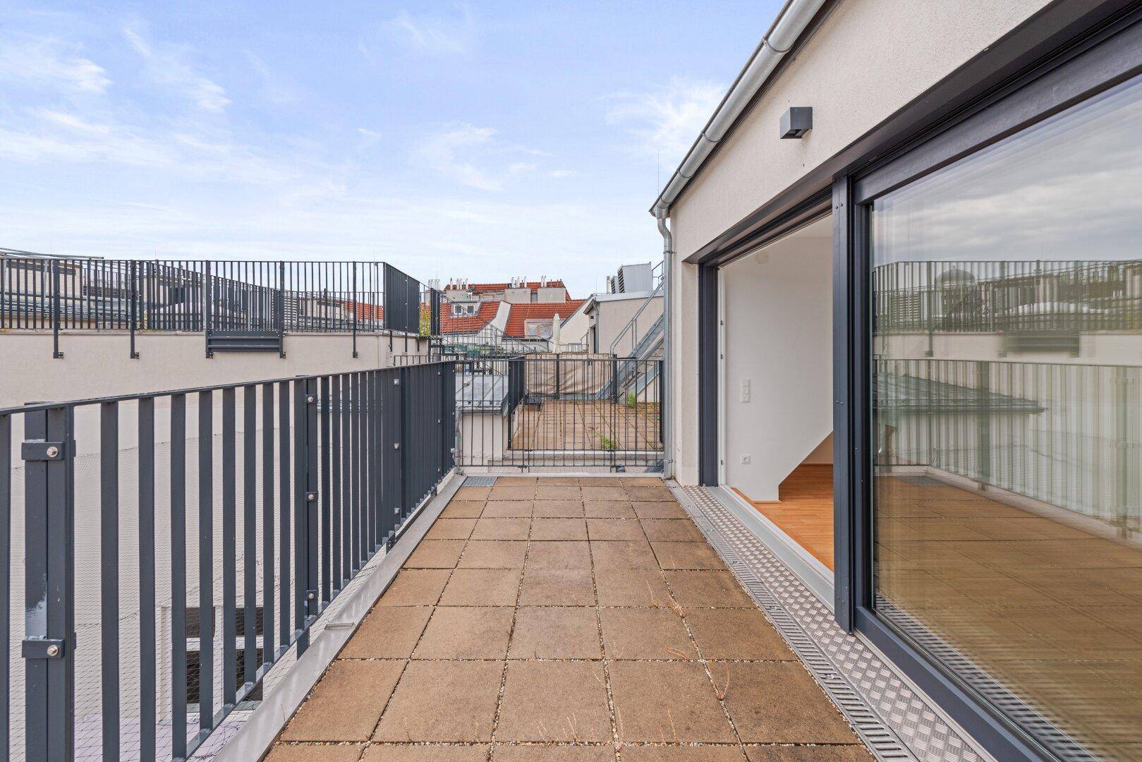 Geräumige Dachterrasse mit Fliesenboden und Schiebetür zum Innenbereich.