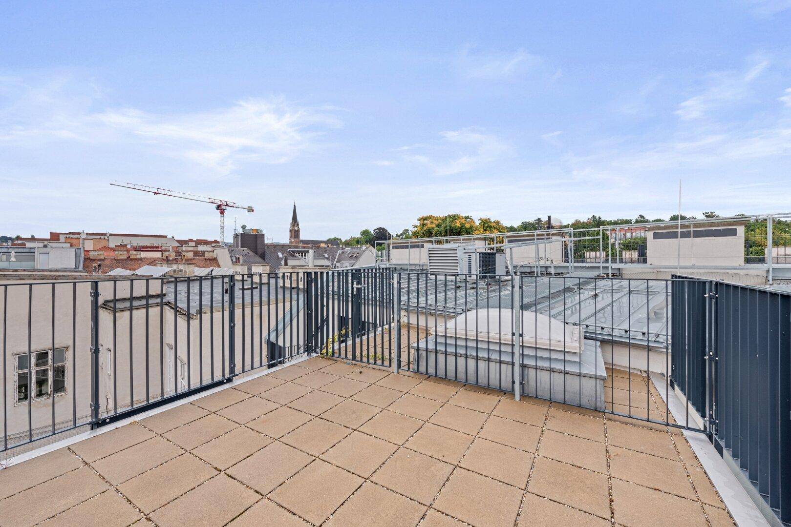 Dachterrasse mit weitem Blick über die Dächer der Stadt und den Himmel.