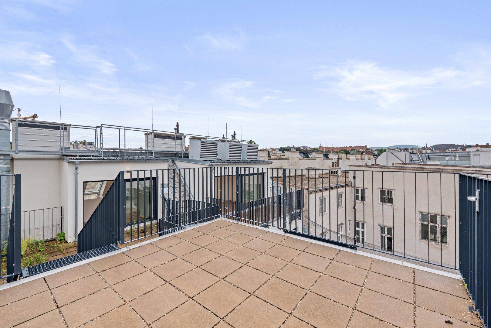 Eckbereich einer Dachterrasse mit Metallgeländer und Blick auf die Umgebung.