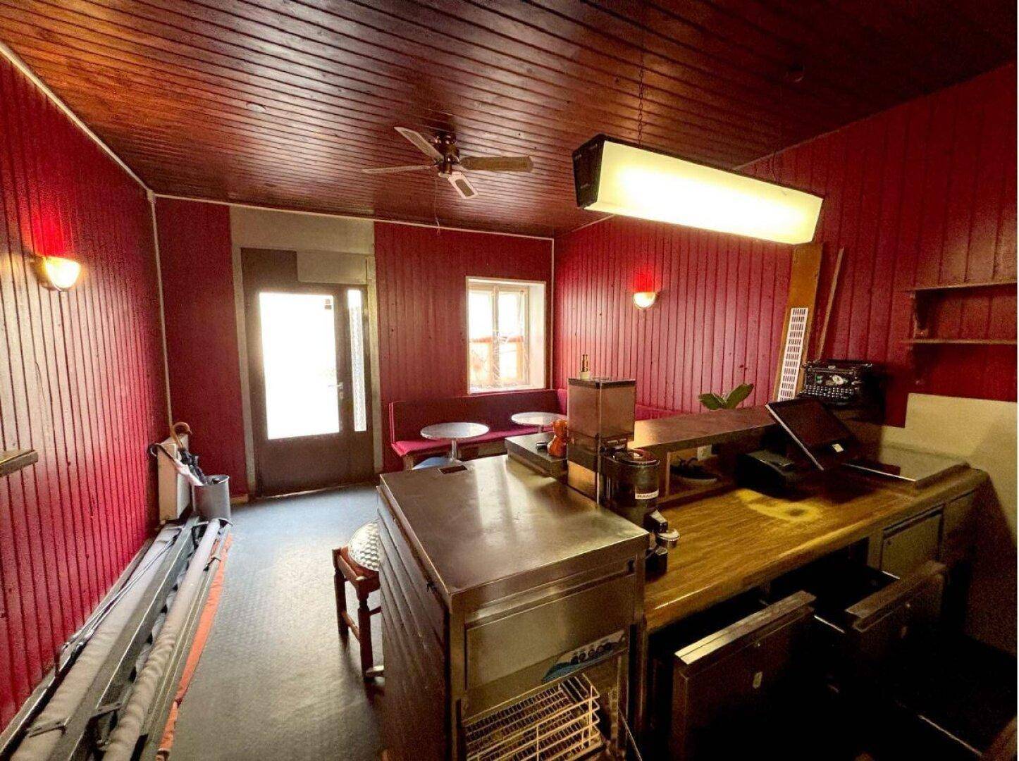Blick auf den Barbereich mit Theke, Deckenventilator und roter Holzverkleidung an Wänden und Decke.