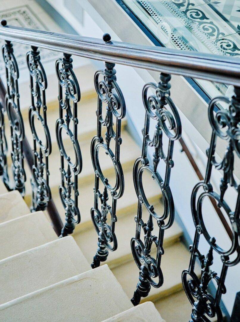 Detailaufnahme eines kunstvoll geschmiedeten Treppengeländers mit eleganten Verzierungen.
