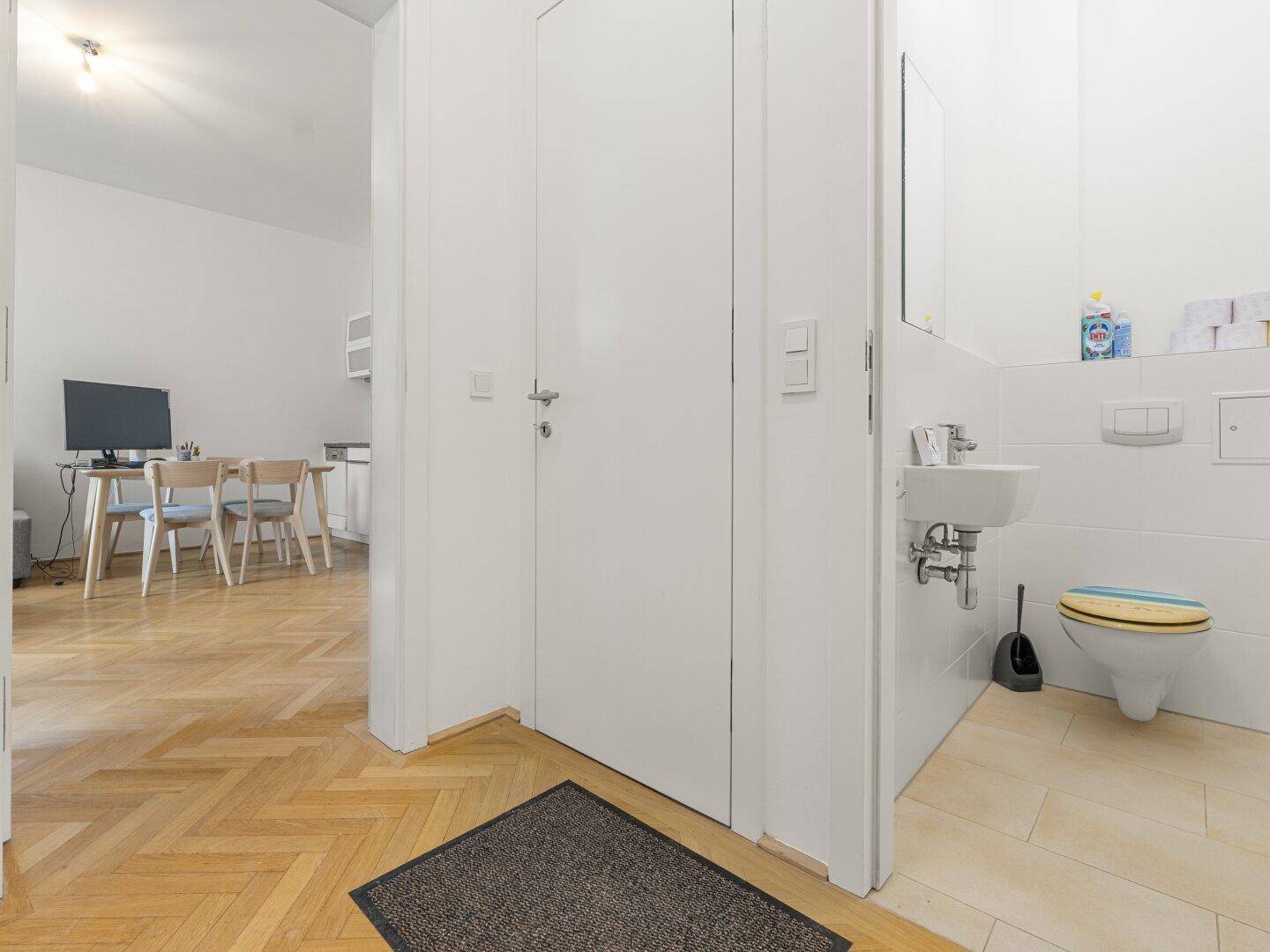 Separates WC mit kleinem Waschbecken und Blick auf den angrenzenden Wohnbereich.