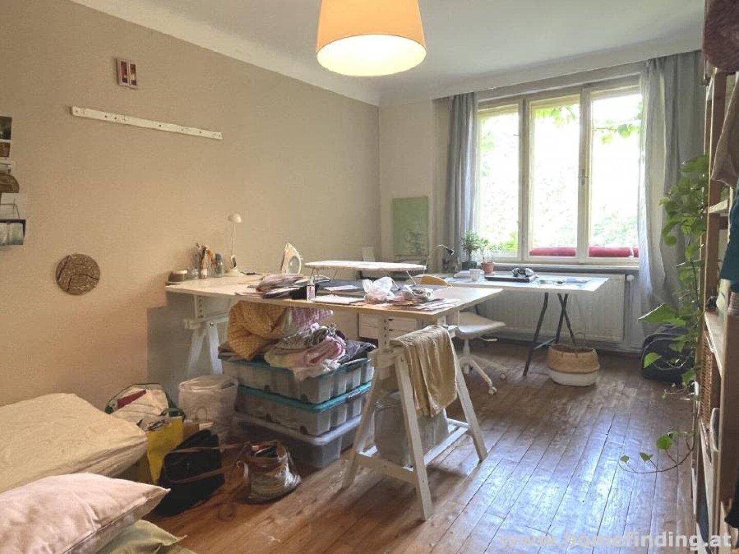Helles Zimmer mit Holzboden, großem Schreibtisch und Blick ins Grüne.