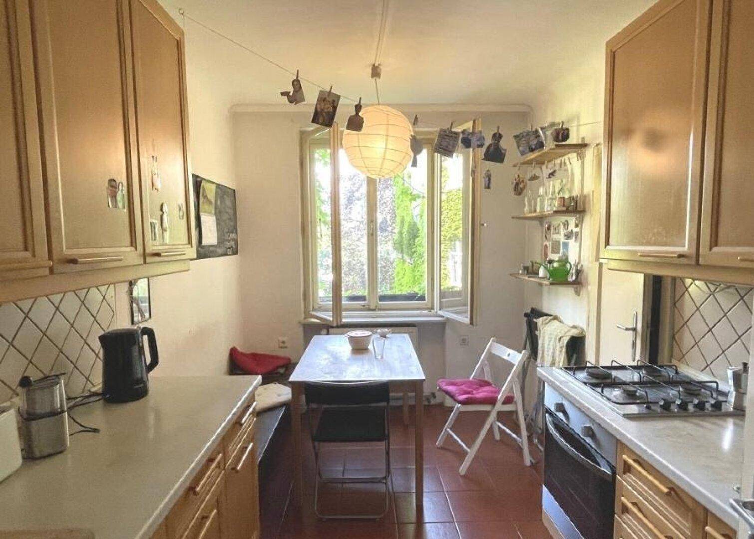 Helle Küche mit Essbereich am Fenster und Holzschränken.