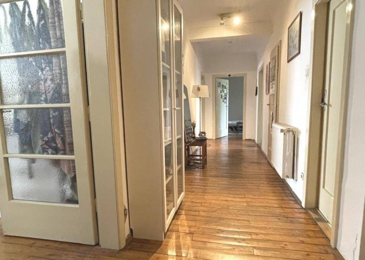 Langer Flur mit Holzboden und Türen zu verschiedenen Räumen.