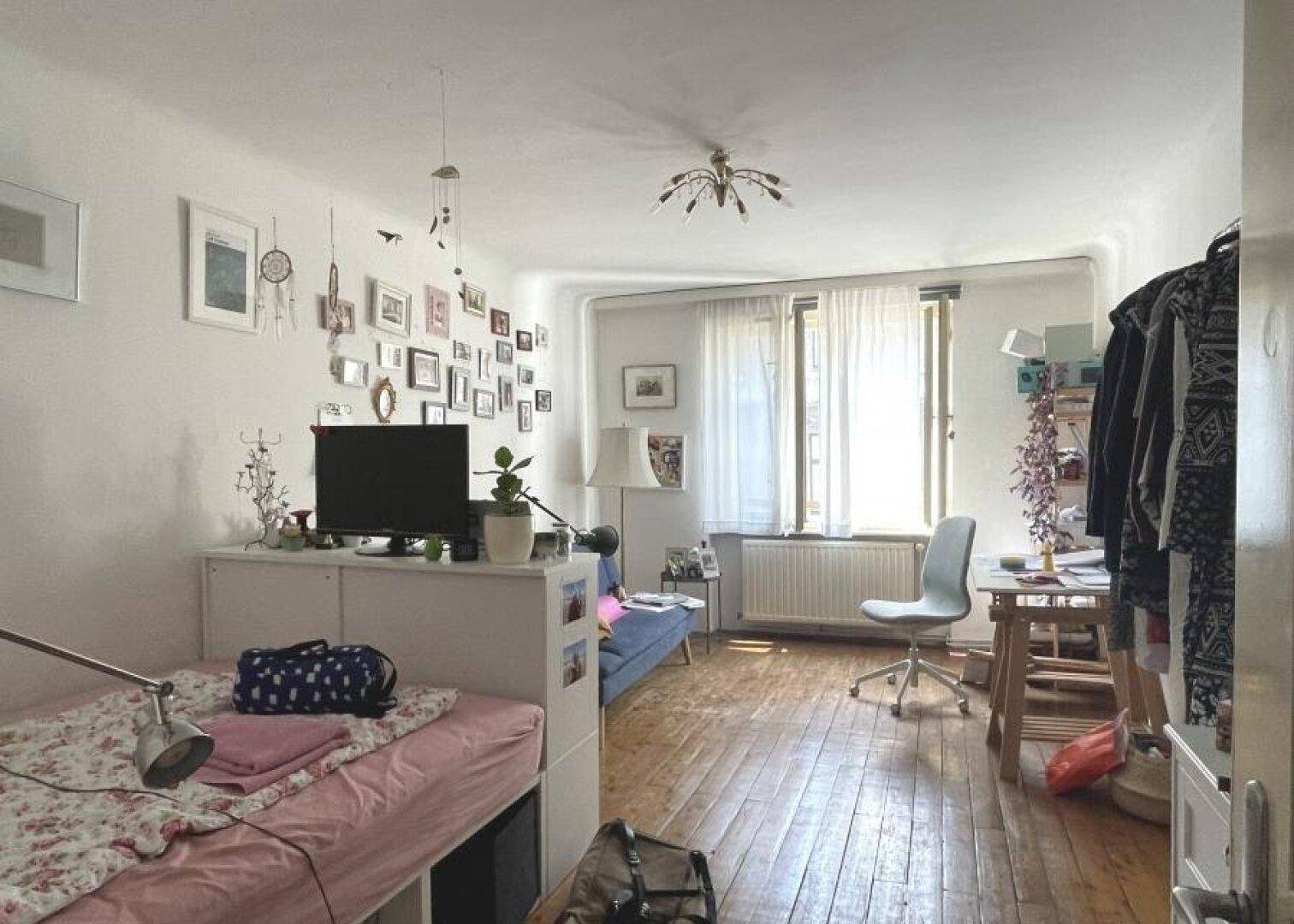 Gemütliches Zimmer mit Holzboden, Bett und vielen persönlichen Dekorationen.
