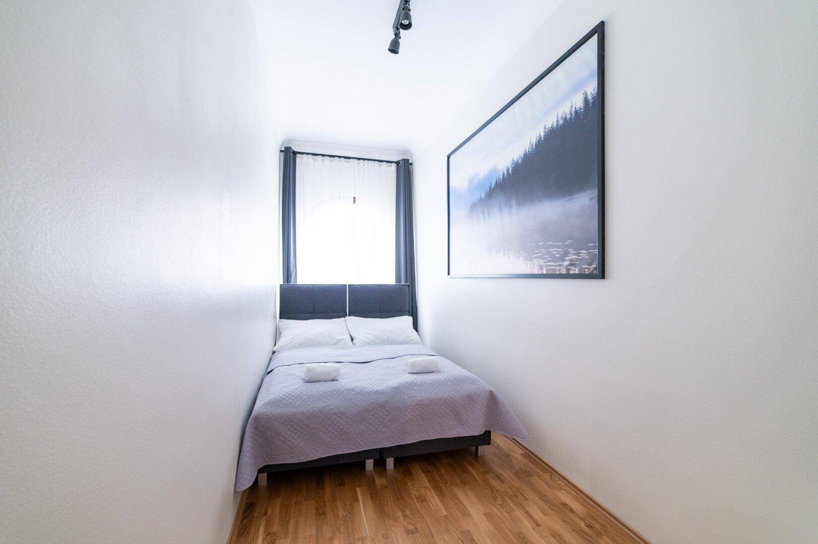 Gemütliches Schlafzimmer mit Doppelbett, Fenster und einem großen Wandbild.