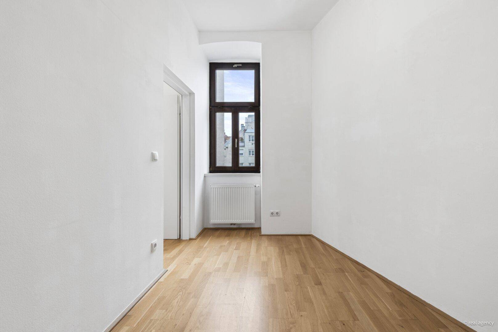 Kleines, helles Zimmer mit Parkettboden und einem Fenster, ideal als Kinder- oder Gästezimmer.