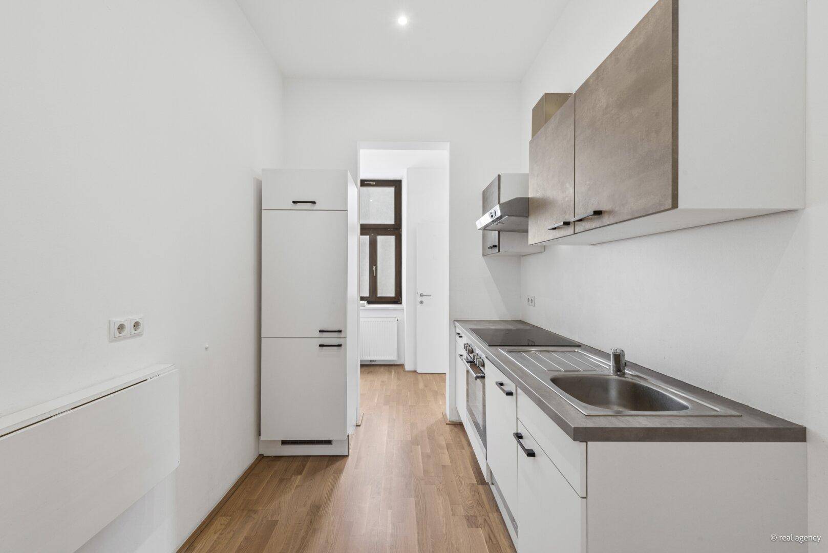Schmale Küchenzeile mit integriertem Kühlschrank und Klapptisch, effizient genutzt.