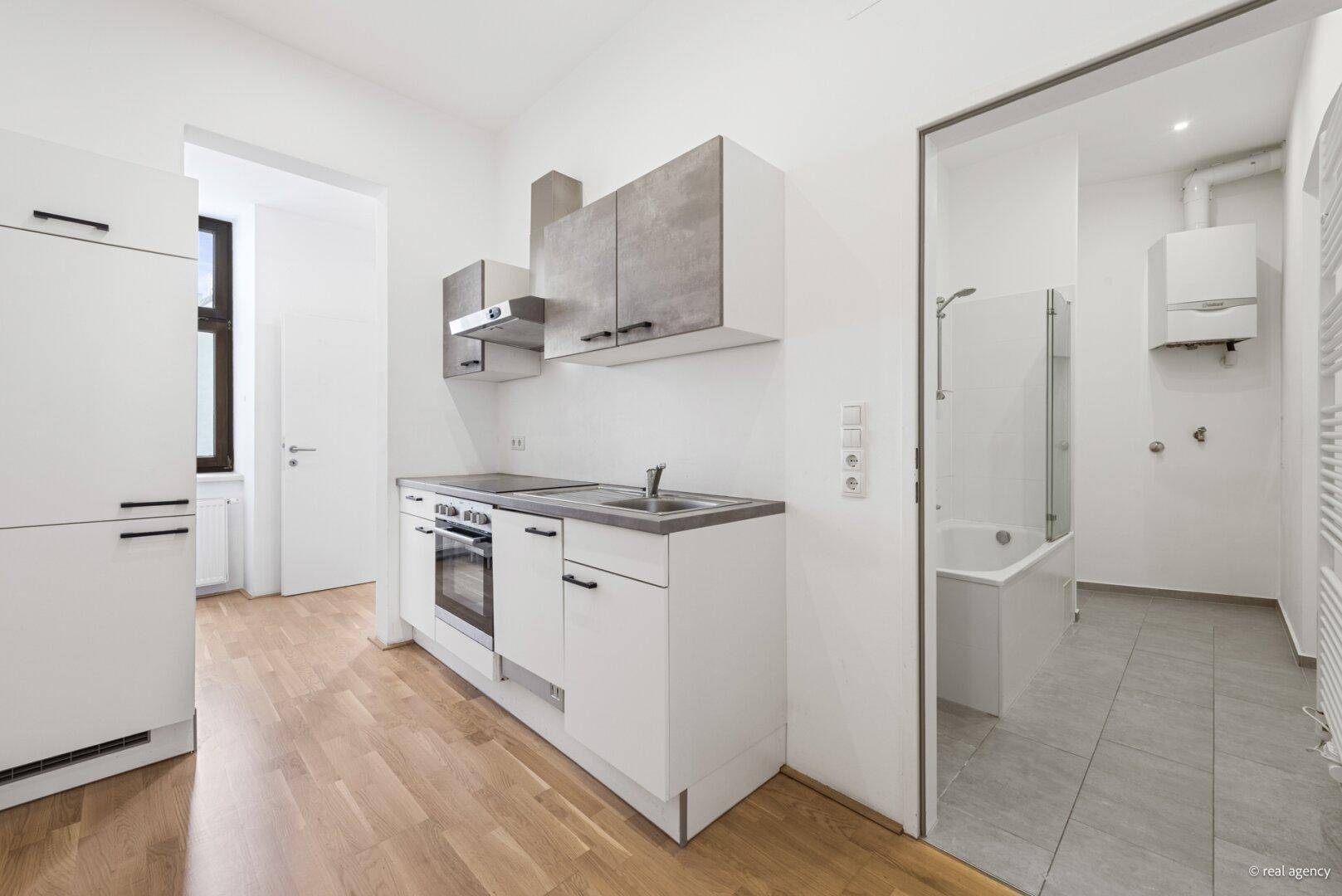 Küchenbereich mit Kühlschrank und Zugang zum Badezimmer, praktisch und funktional gestaltet.