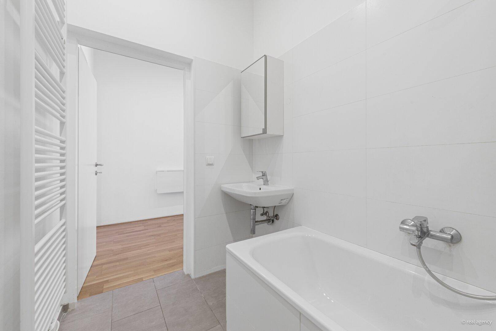 Modernes Badezimmer mit Badewanne, Waschbecken und weiß gefliesten Wänden.