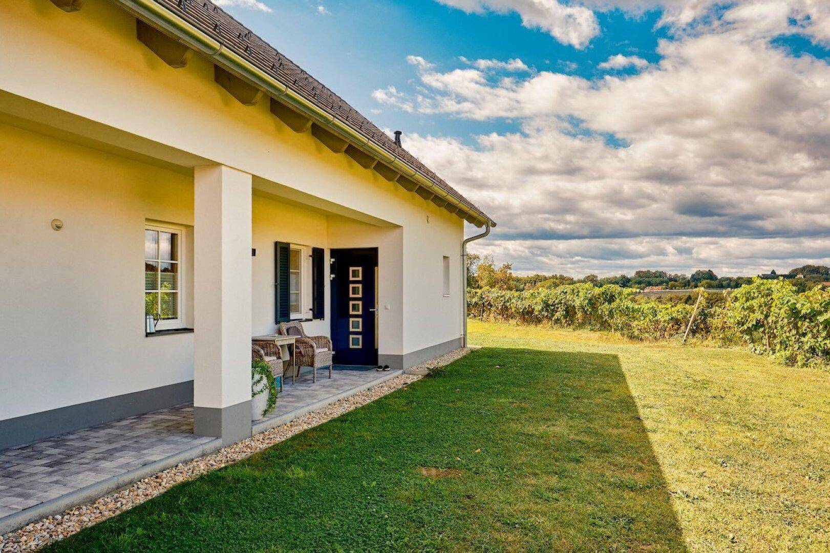 Vorderseite des Hauses mit gepflegtem Rasen und überdachtem Eingangsbereich.