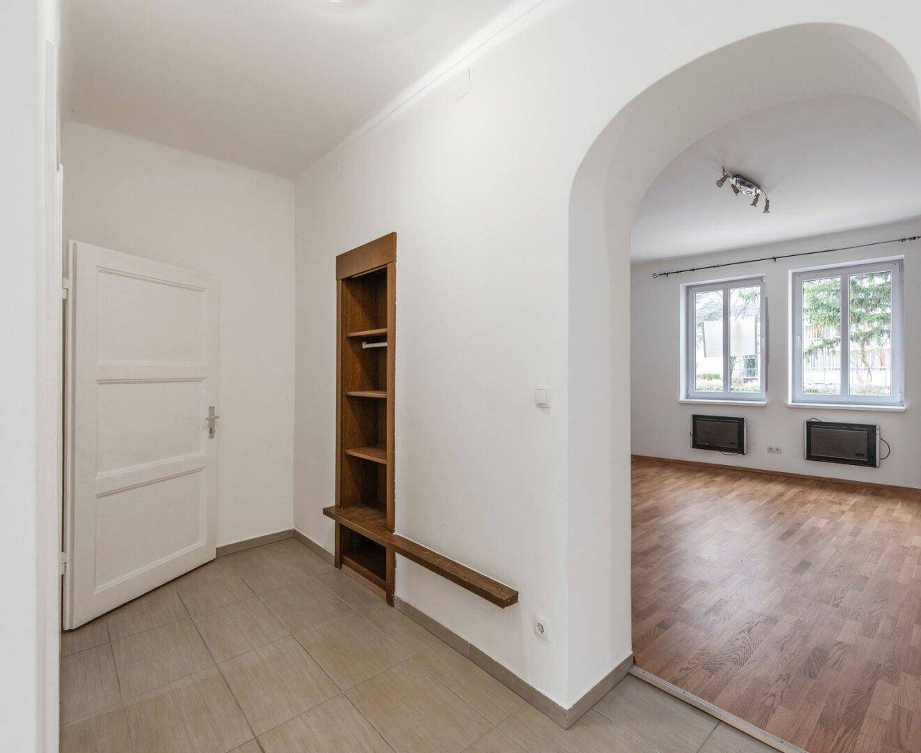 Eingangsbereich mit Fliesenboden, integriertem Regal und offenem Zugang zum Wohnbereich.