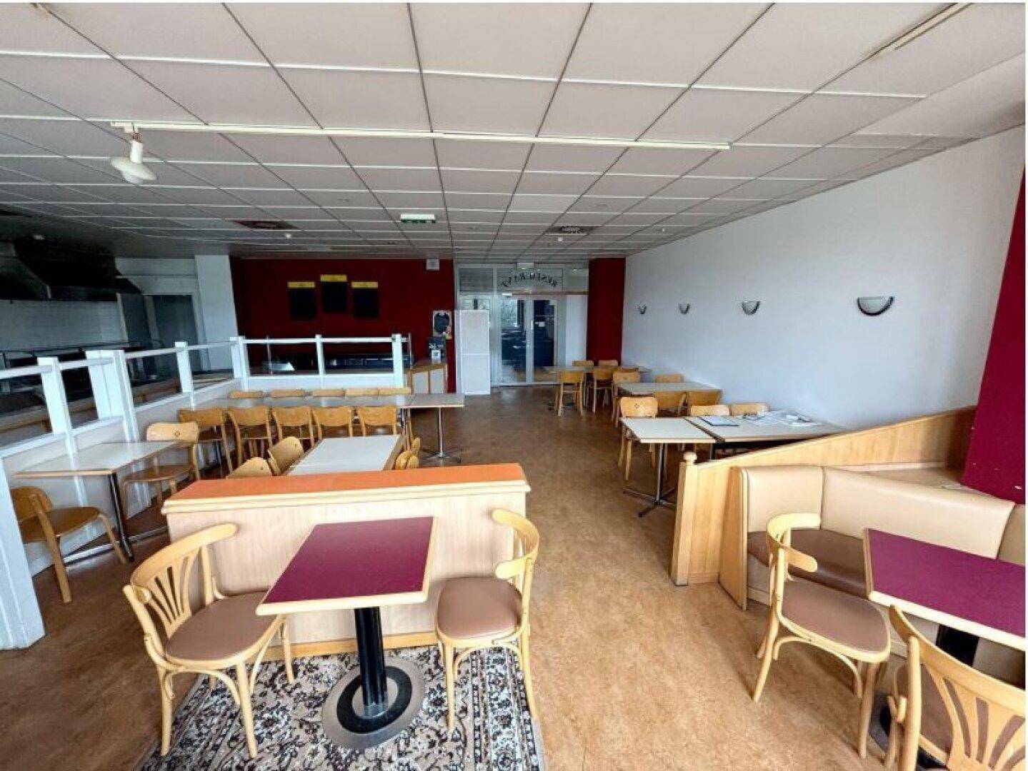 Gemütlicher Restaurantbereich mit verschiedenen Sitzmöglichkeiten, Teppichakzenten und einer roten Wand.