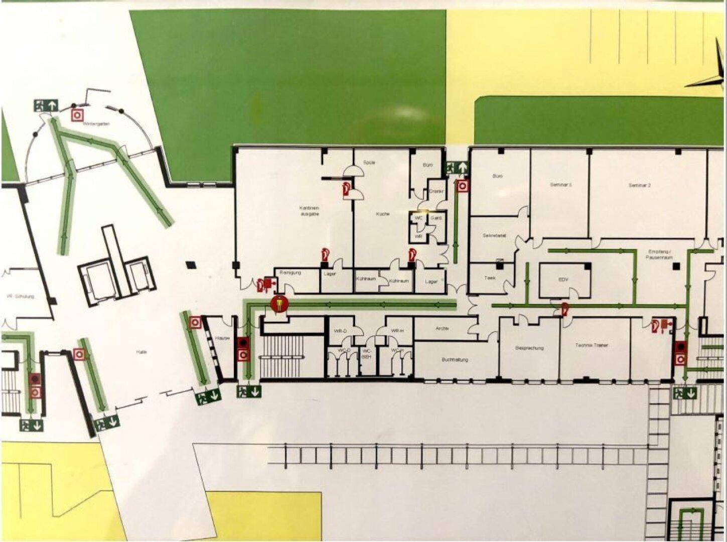 Detaillierter Grundrissplan mit Notausgängen und Raumaufteilung eines Gebäudes, inklusive Außenbereichen.