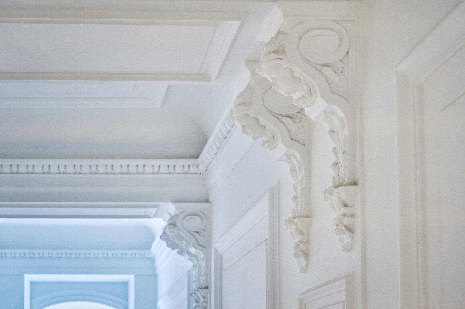 Nahaufnahme von kunstvollen Stuckverzierungen an Wand und Decke in einem historischen Gebäude.