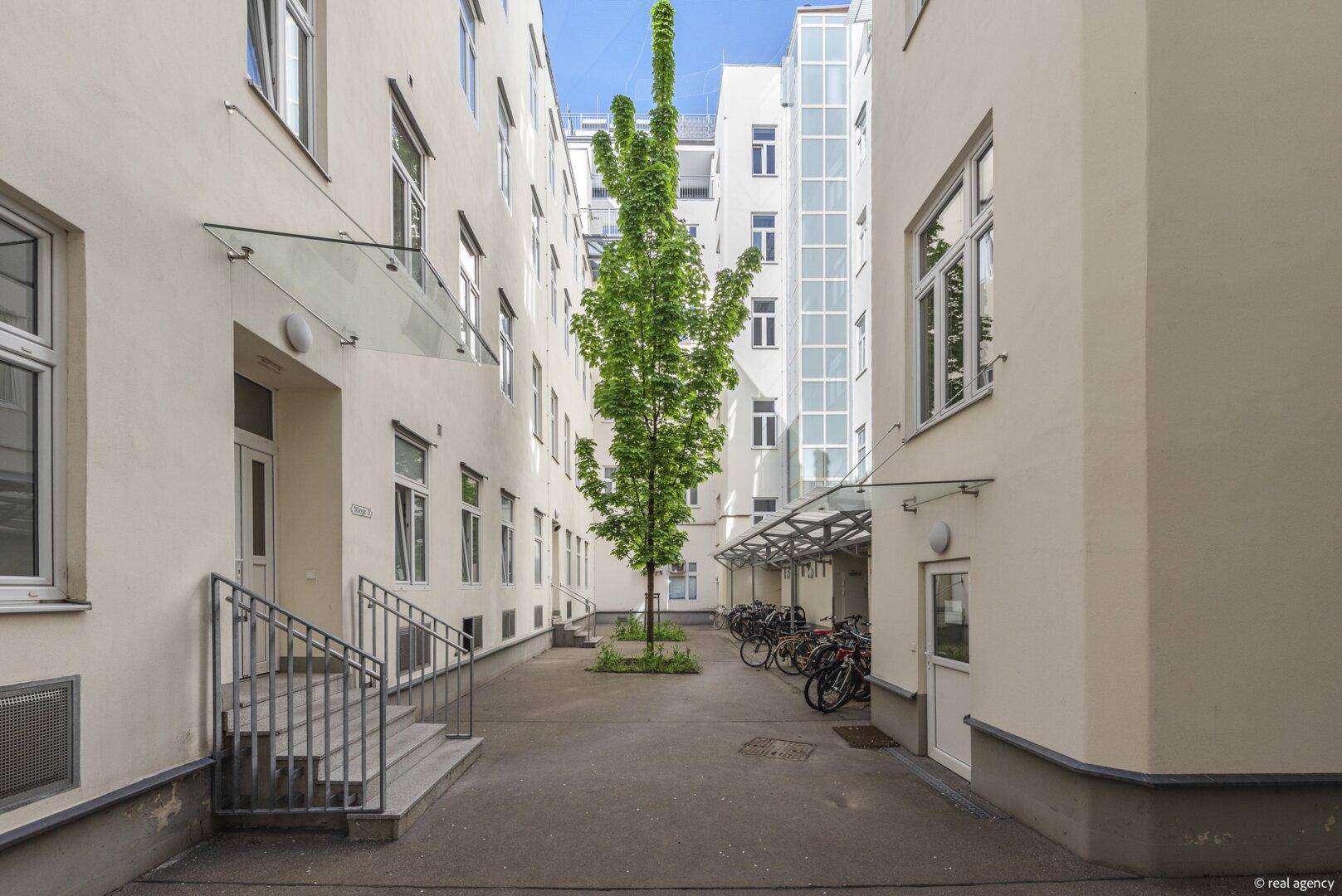 Begrünter Innenhof mit Fahrradstellplätzen und mehreren Gebäudeeingängen.
