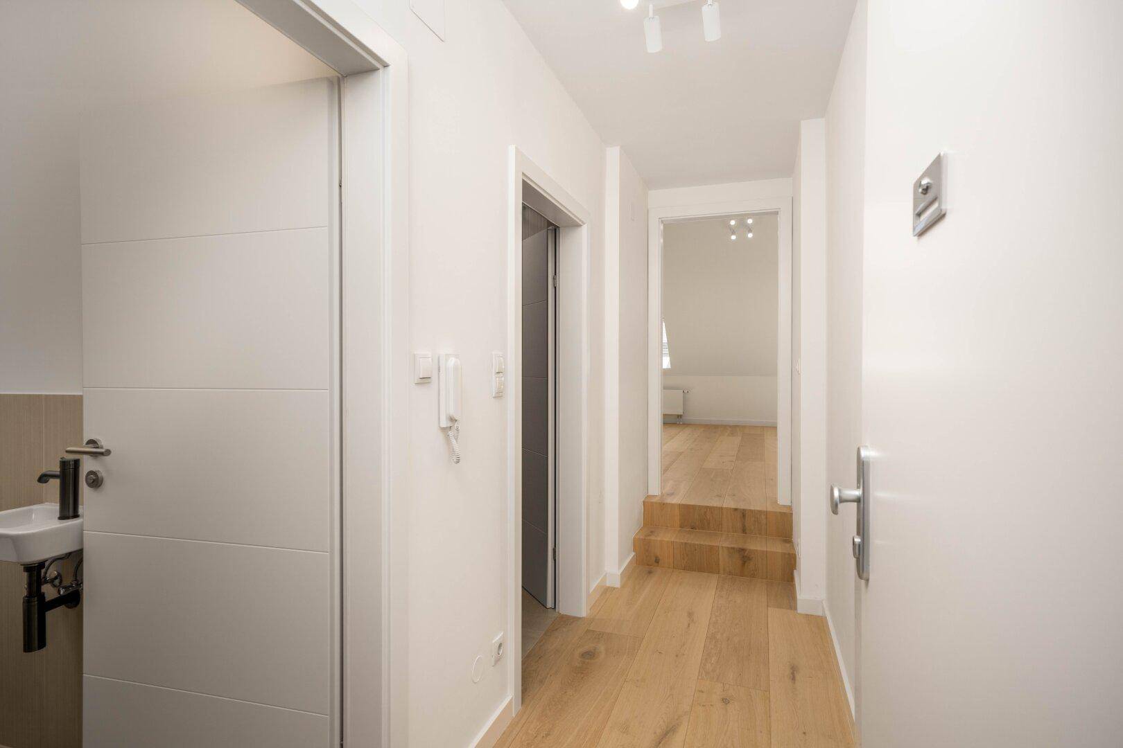 Heller Flur mit Holzfußboden, der zu weiteren Räumen und einem Gäste-WC führt.