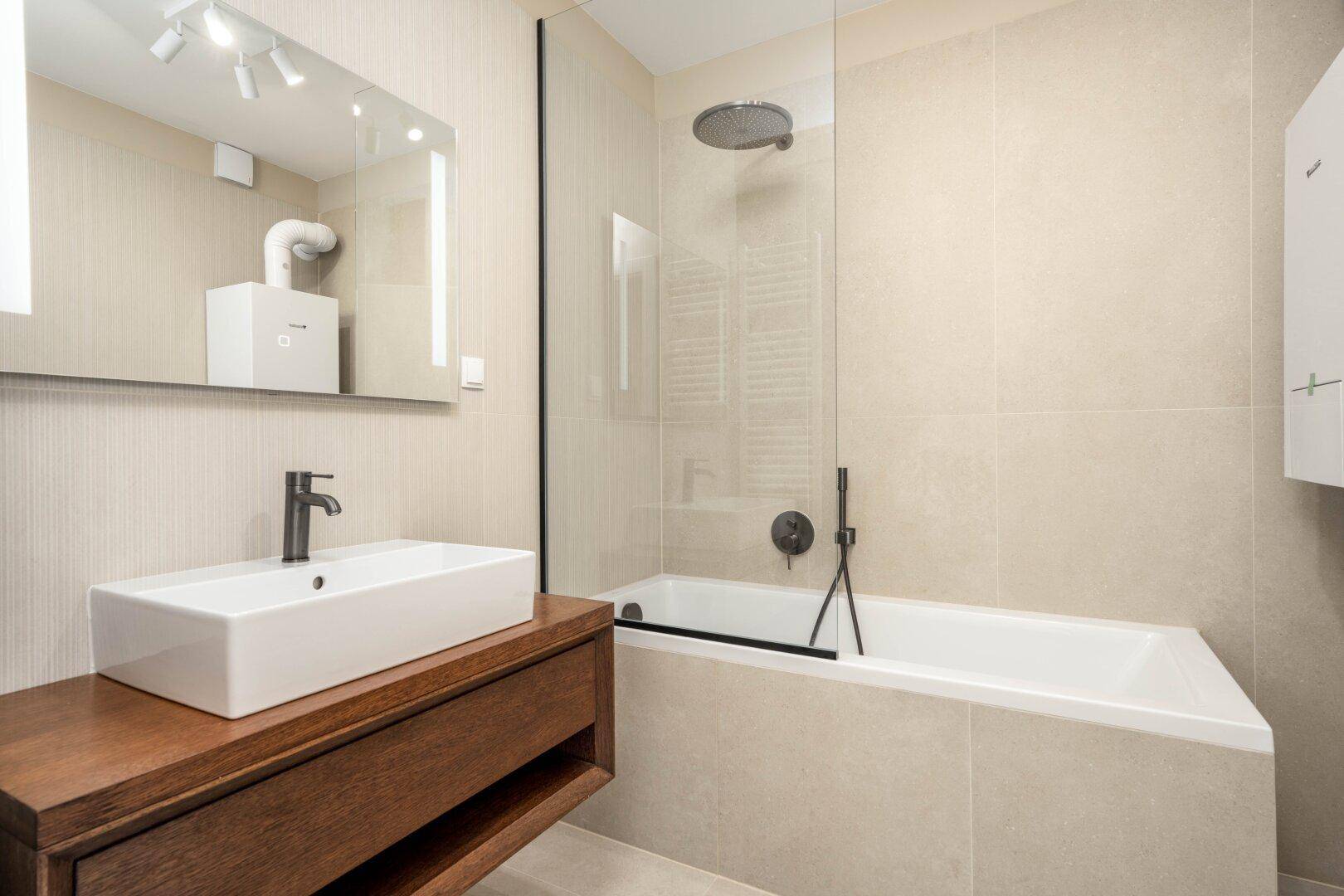 Modernes Badezimmer mit Badewanne, Dusche, elegantem Waschbecken und beigen Fliesen.
