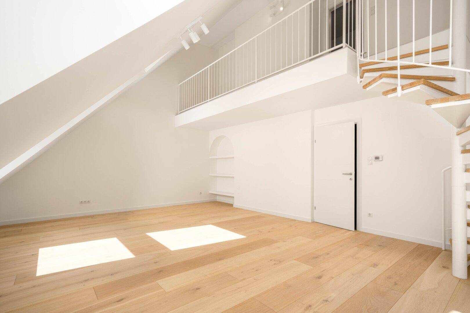 Geräumiger Dachgeschossraum mit Holzboden, Wendeltreppe und offener Galerie, hell und modern.