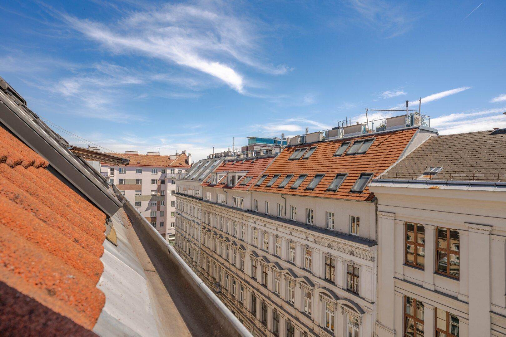 Panoramablick über die Dächer der Stadt mit historischen Gebäuden und Ziegeldächern unter blauem Himmel.