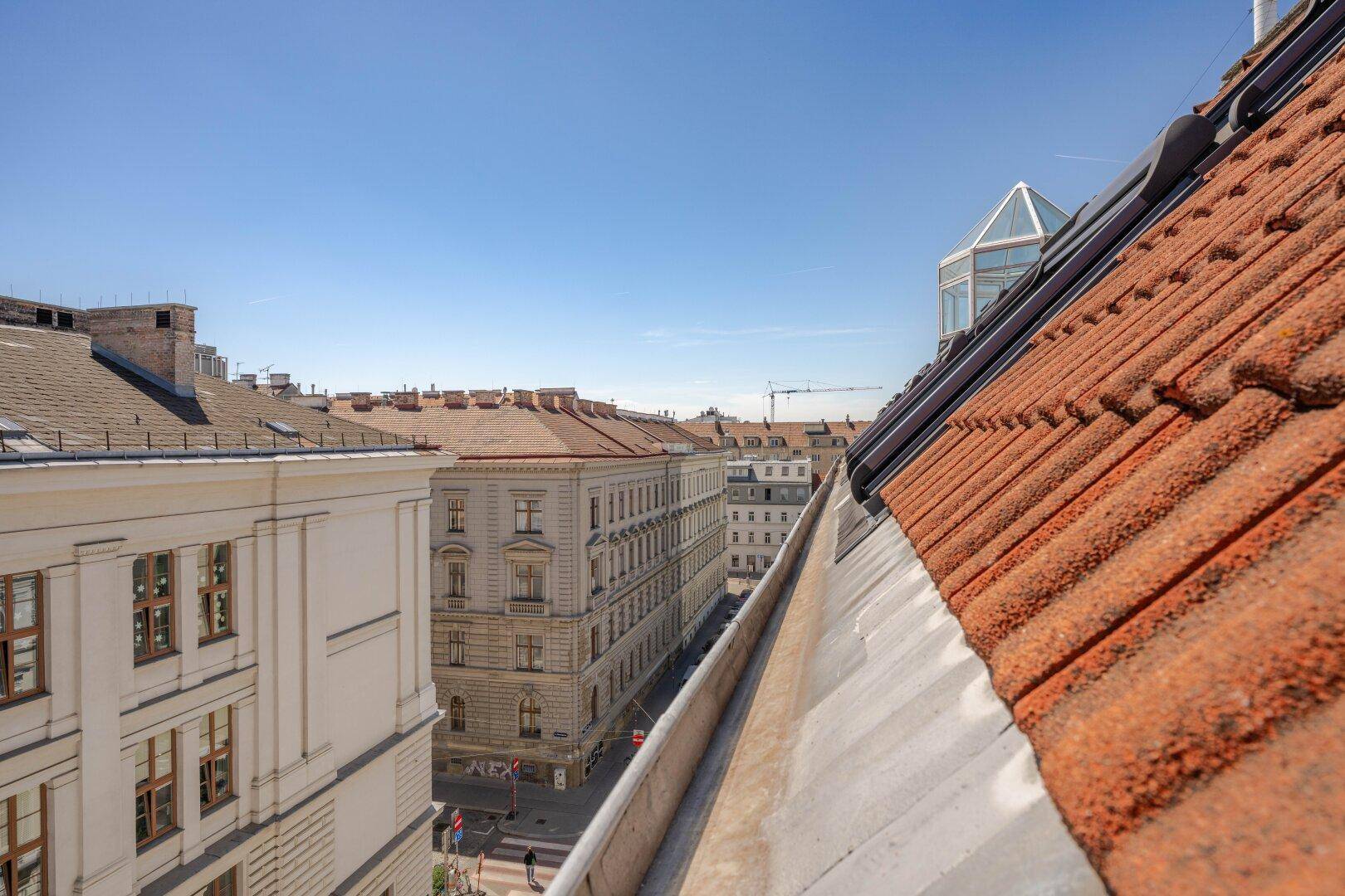 Blick über die Dächer einer Stadtstraße mit traditionellen Ziegeldächern und historischen Gebäuden.