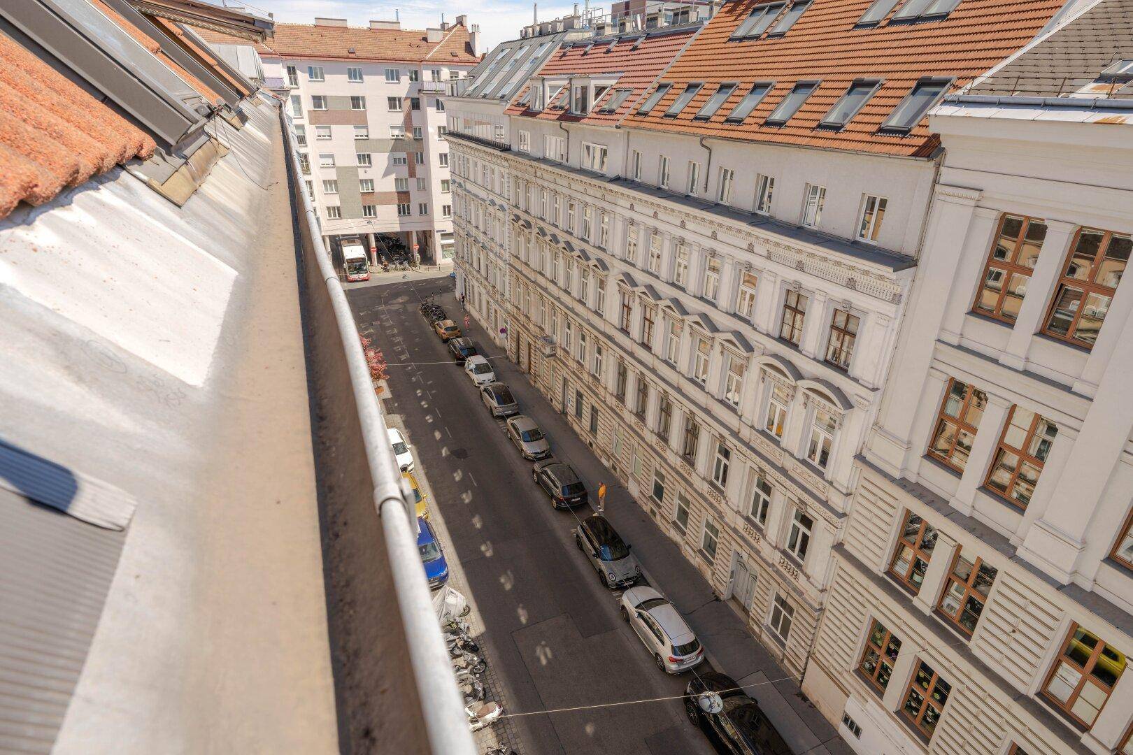 Weitblick über eine ruhige Stadtstraße mit geparkten Fahrzeugen und klassischer Architektur.