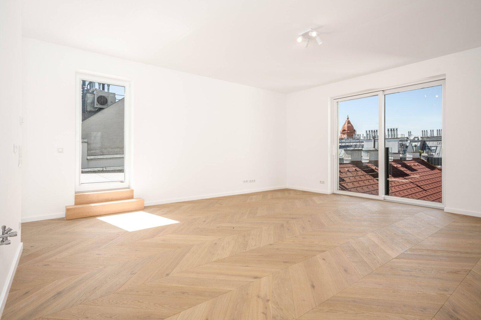Lichtdurchflutetes Wohnzimmer mit Holzboden und Schiebetüren zu einem Außenbereich mit Stadtblick.