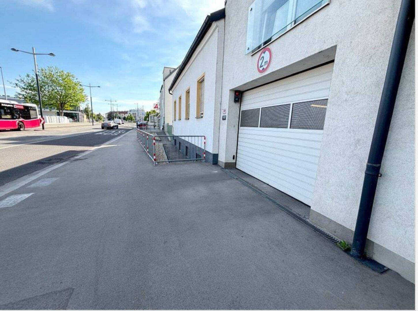 Außenansicht eines Gebäudes mit Garagentor und Zufahrt von der Straße.