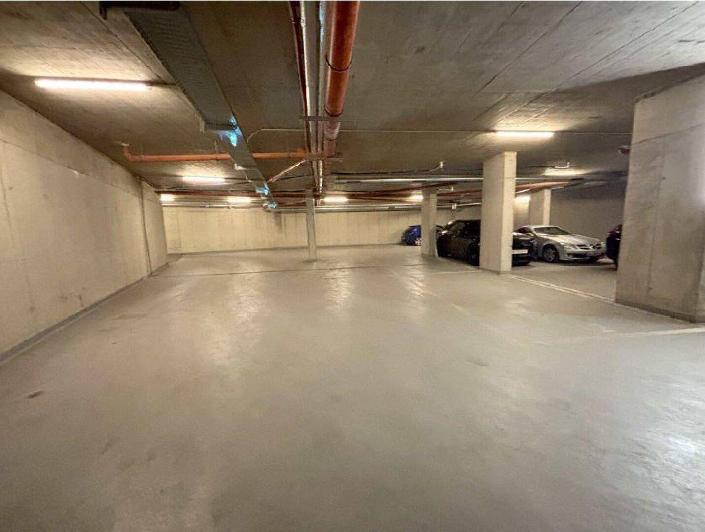 Helle und saubere Tiefgarage mit ausreichend Platz für mehrere Fahrzeuge.