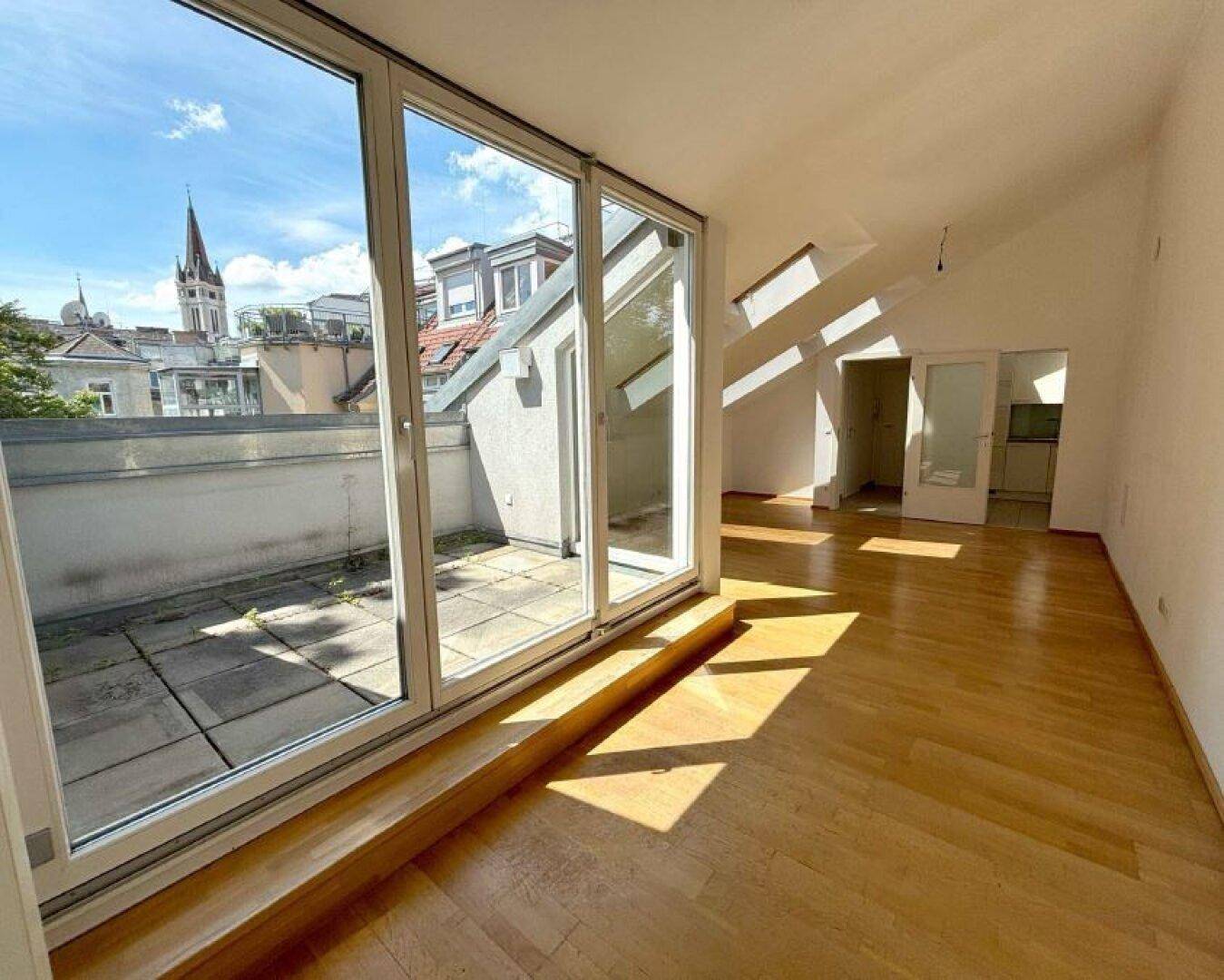 Lichtdurchfluteter Wohnbereich mit Parkettboden, großen Glasfronten und direktem Zugang zur Dachterrasse.