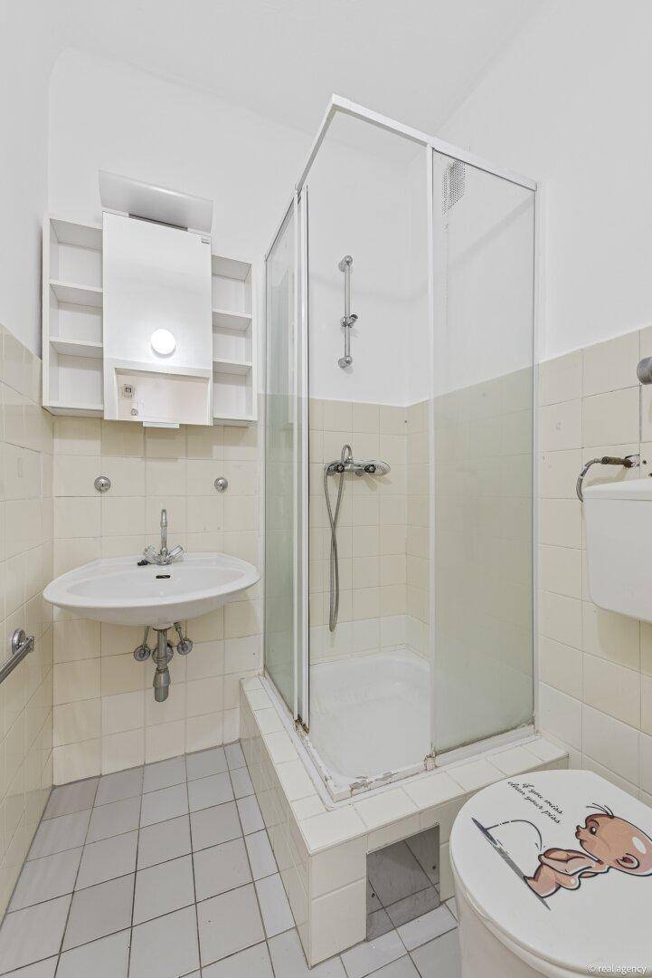 Funktionales Badezimmer mit Duschkabine, Waschbecken und WC, ausgestattet mit hellen Fliesen.