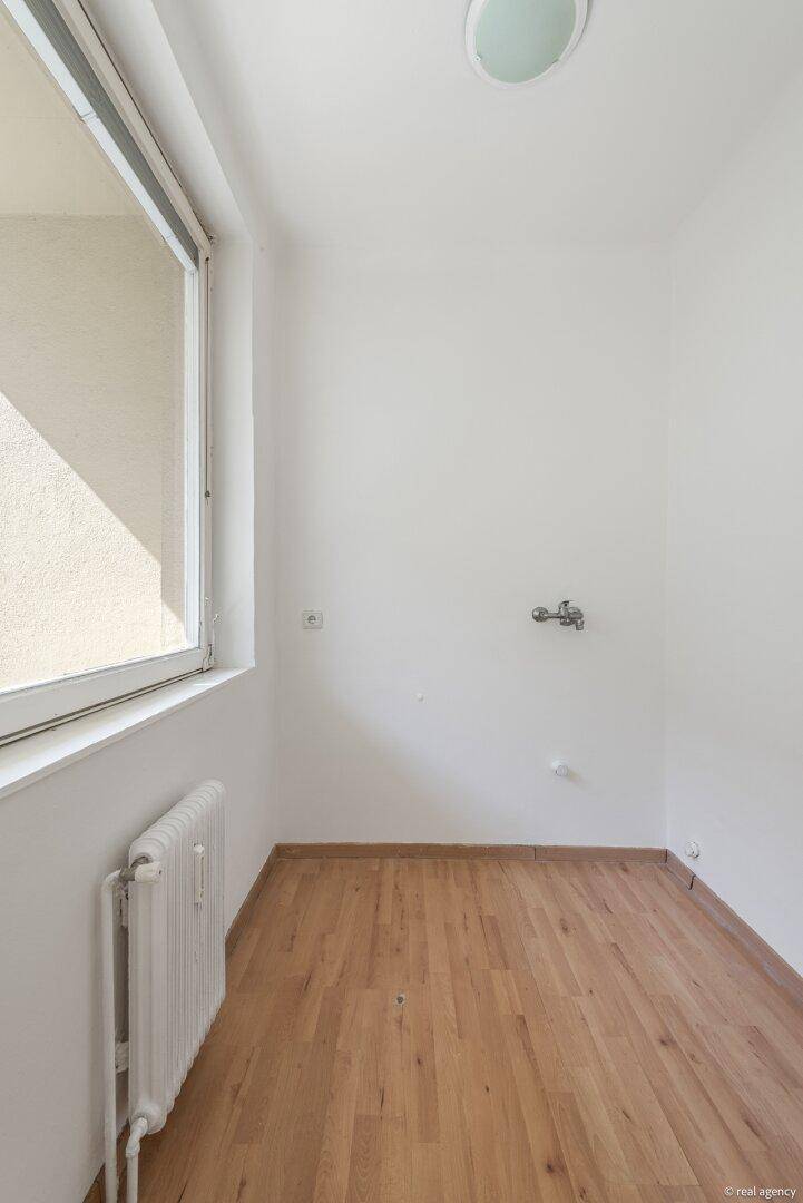Heller Hauswirtschaftsraum mit Fenster, Heizung und Wasseranschluss, bereit für individuelle Nutzung.