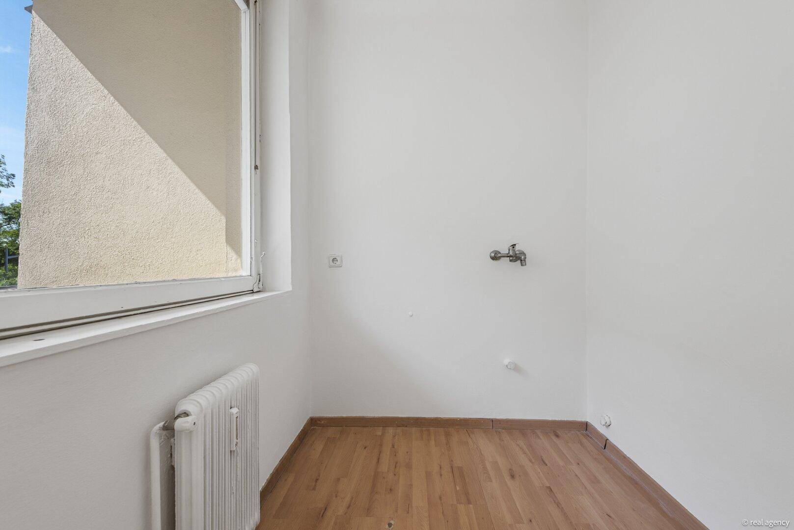 Kleiner Raum mit Fenster, Heizkörper und Wasseranschluss, ideal als Hauswirtschaftsraum oder kleine Küche.