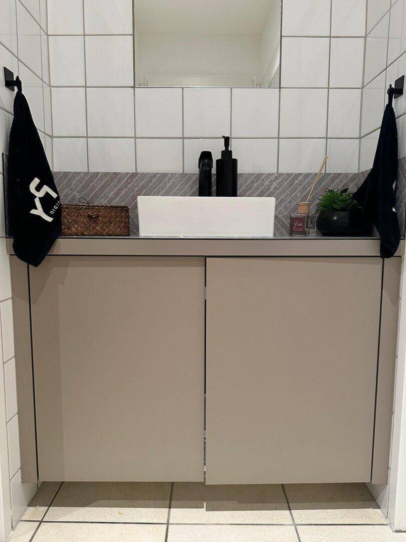 Modernes Badezimmer mit stilvollem Waschtisch, schwarzer Armatur und weißen Fliesen, bietet eine saubere Ästhetik.