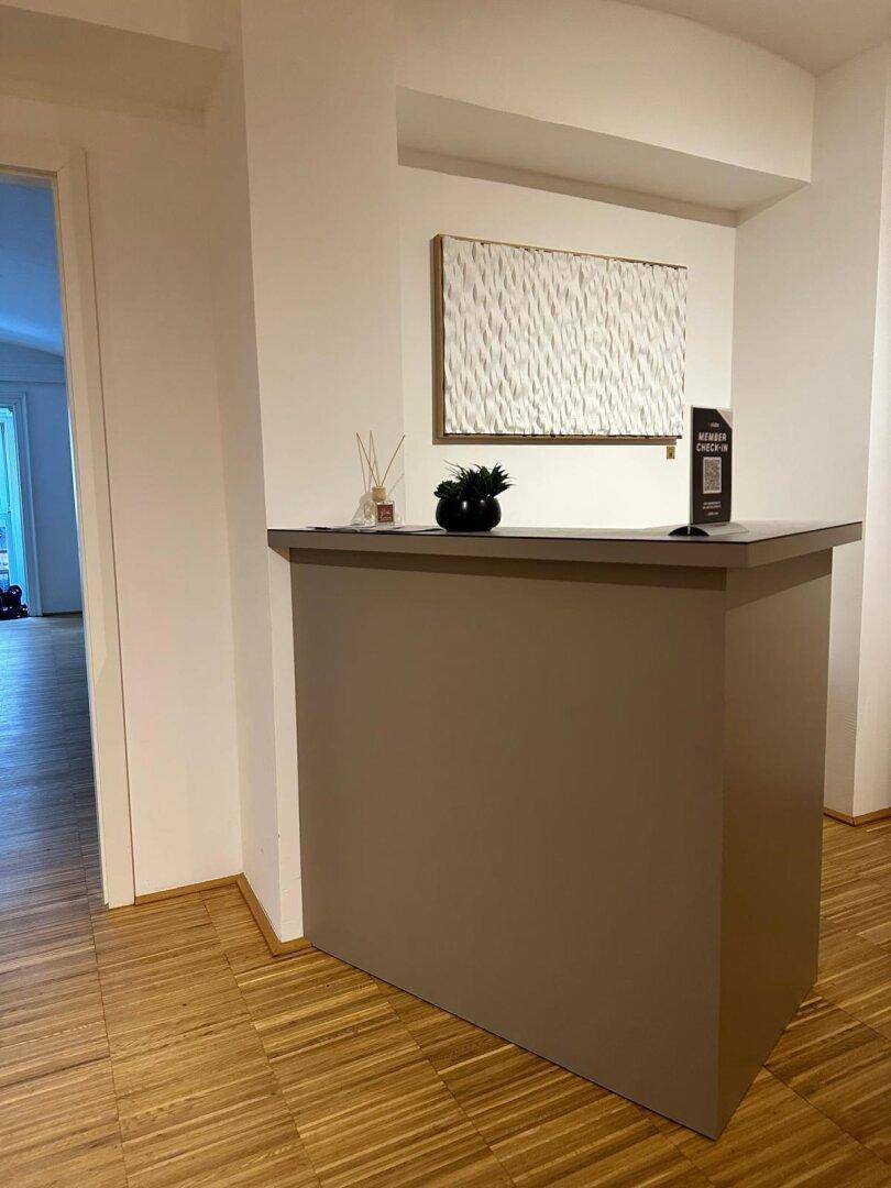 Empfangsbereich mit moderner Theke und Kunstwerk an der Wand, schafft einen einladenden ersten Eindruck.