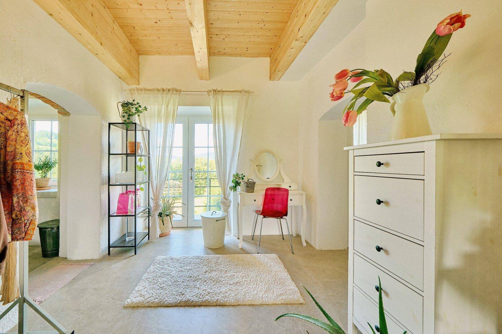 Heller Ankleidebereich oder Schlafzimmer mit Schminktisch, Regalen und Zugang zum Außenbereich.
